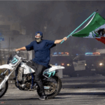 Motociclista sostiene la bandera de México en medio de humareda